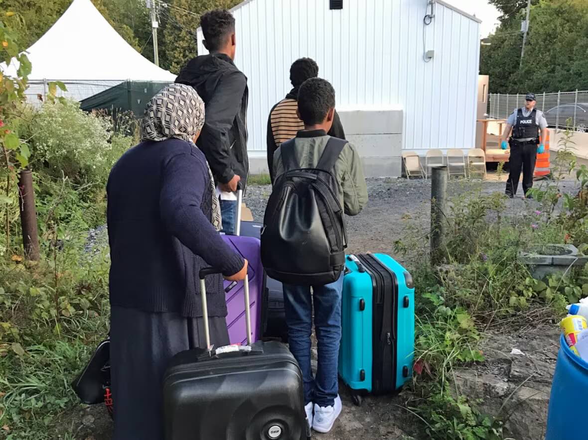 La police rencontre des personnes qui traversent la frontière canadienne le long du chemin Roxham, au Québec. La routine est pratiquée et ordonnée alors que les arrivants attendent les avertissements de la GRC concernant une entrée illégale, puis traversent. Il n'y a pas de retour en arrière pour cette famille : elle sera emmenée dans un établissement plus grand pour commencer sa demande de statut de réfugié. Parmi les réclamations déjà entendues, environ 55 pour cent ont été acceptées. (Susan Ormiston/CBC)<br /><br />Source: https://www.cbc.ca/news/canada/the-national-roxham-road-immigration-border-1.5169249